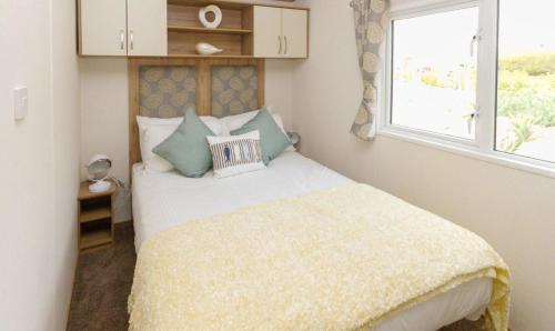 a bedroom with a bed with a yellow blanket and a window at Moffat Manor Holiday Resort in Beattock