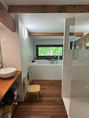 a bathroom with a tub and a sink and a chair at Gîte du Séquoia - Paisible maison de campagne in Vallet