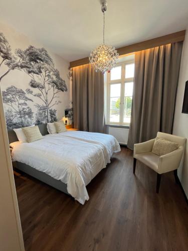 a bedroom with a large bed and a chandelier at Vänerport Stadshotell i Mariestad in Mariestad