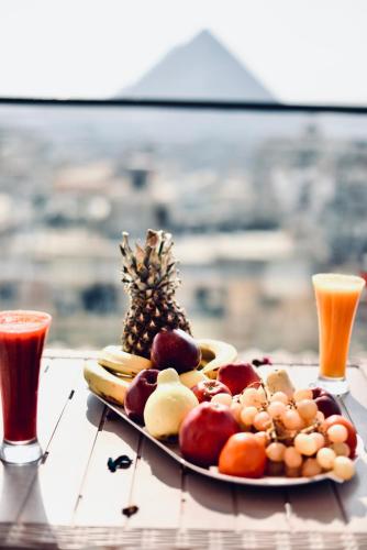 开罗Legend Pyramids Inn Hostel的桌上一盘水果和两杯饮料