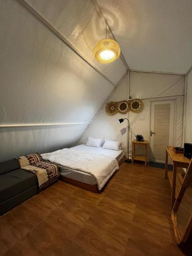 a bedroom with a bed and a couch in a room at D'River Luxcamp in Cisarua