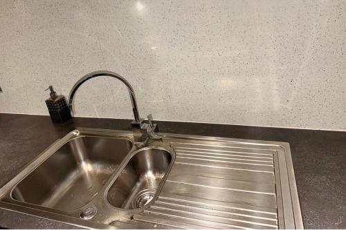 2 Bedroom Apartment - Sleeps 4 Free Parking Wifi في Pollokshaws: بالوعة مع صنبور في المطبخ