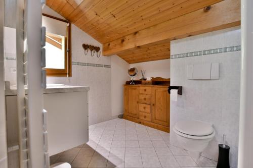 baño con aseo y techo de madera. en Chalet Anou - proche pistes de ski, en Le Chinaillon