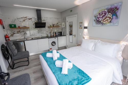 a bedroom with a large white bed and a kitchen at Casa da Mãe in Santana