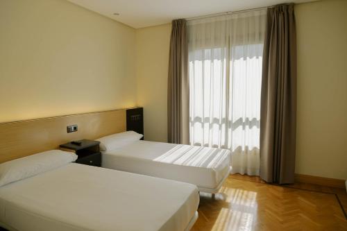 a hotel room with two beds and a window at Hotel Eibar in Éibar
