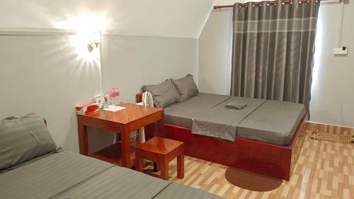 une petite chambre avec deux lits et un bureau dans l'établissement ណាវិតាយ៉ារី បឹងហ្គាឡូ Navitayary Bungalow, à Krong Saen Monourom