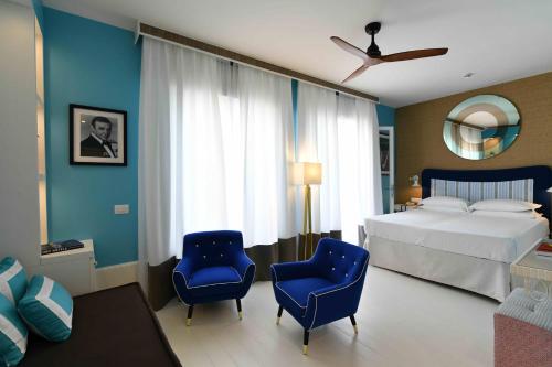 a bedroom with a bed and two blue chairs at Hotel Majestic in Lido di Jesolo