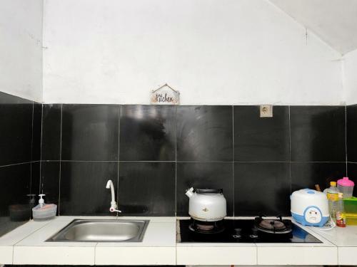 une cuisine avec un évier, une plaque de cuisson et des carreaux noirs dans l'établissement Aurora villa Dieng, à Diyeng