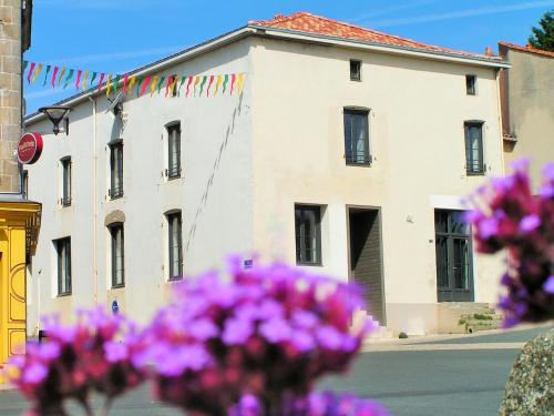 un edificio con banderas y flores moradas en la parte delantera en Les Glaneuses gîte Entre Amis centre-bourg à 3 min du Puy duFou, en Les Épesses