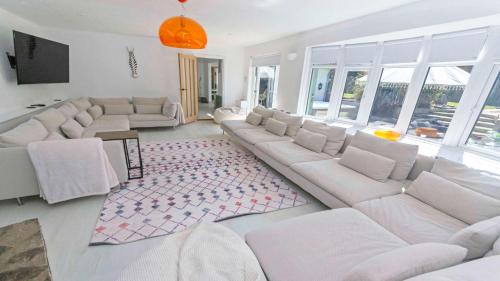 Elle comprend un salon doté d'un mobilier blanc et d'un grand canapé. dans l'établissement Shippenrill Croyde - Sleeps 14 - Hot Tub option - Stylish Home with fire pit, table tennis & dog friendly, à Croyde