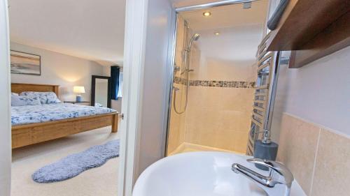 ein Badezimmer mit Waschbecken und Dusche und ein Bett in der Unterkunft Ladywell Croyde - Super stylish large home with pool table, woodburner, pizza oven and Hot Tub Option, Sleeps 12 in Croyde