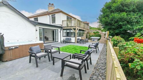 a patio with chairs and a tub in a house at Bag-End House - Unique home with Balcony, Beautiful Views, Ping Pong and Hot Tub option - Sleeps 14 in Croyde