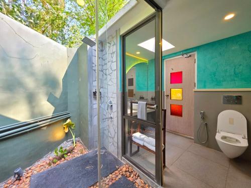 een badkamer met een toilet en een glazen wand bij Vedic Village Retreat Kodungallur in Cochin