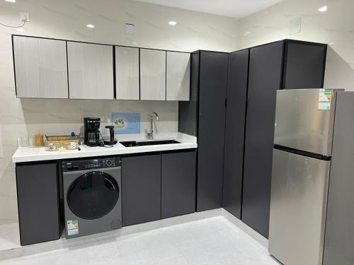 uma cozinha com armários a preto e branco e uma máquina de lavar louça em تلال الفخامة em Hail