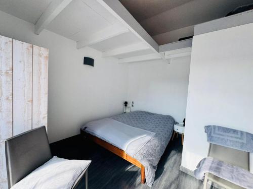 a small bedroom with a bed and a chair at La Paillote in Loctudy