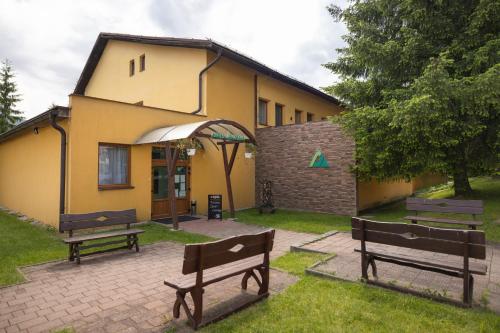 a building with two benches in front of it at Hotel Orava in Dolný Kubín