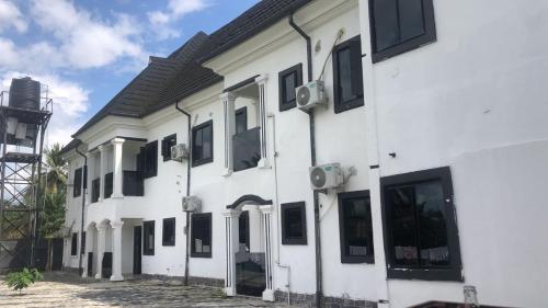 a white building with black windows on it at Vivi apartment hotel and suite in Sapele