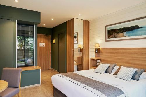 a bedroom with a large bed and a table at La Cremaillere Hôtel-Restaurant in Courseulles-sur-Mer