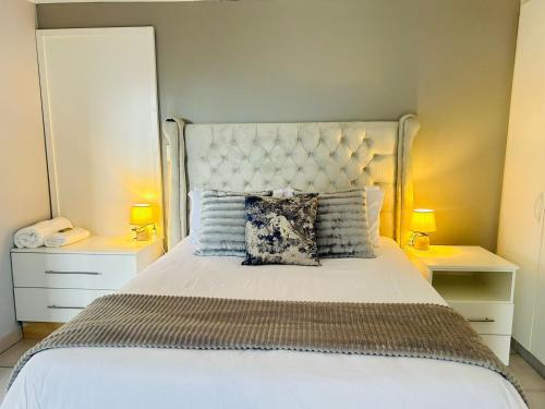 a bedroom with a large white bed with two lamps at Richards Bay Serenity Retreat Apartments in Richards Bay