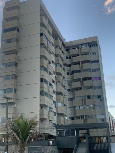 a tall building with a palm tree in front of it at Maison Chateaubriand Residence in Maceió