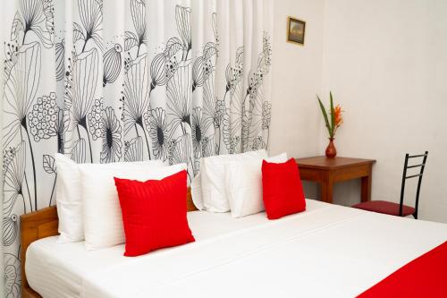 une chambre avec un lit blanc avec des oreillers rouges dans l'établissement Altura Villa Galle, à Galle