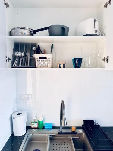 MetaWise Cozy Retreat close to Monash Uni and Chadstone U3 في Oakleigh South: طاولة مطبخ مع حوض وبعض الأطباق