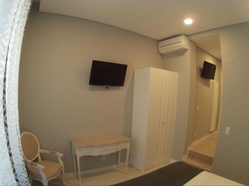 a room with a tv on the wall and a table at Pensao Estacao Central in Lisbon