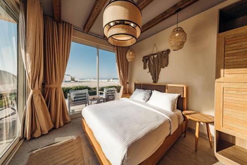a bedroom with a bed and a large window at Azur White Resort Ras El Hekma in Zāwiyat al ‘Awwāmah