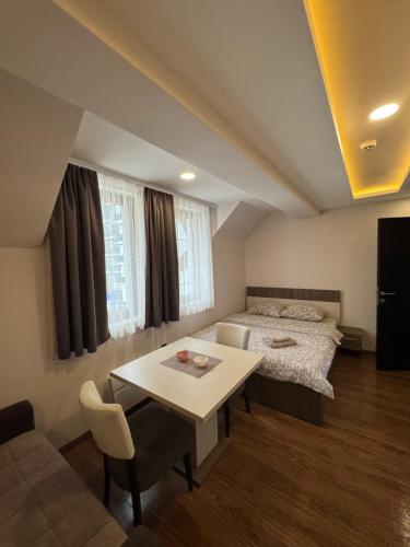 a room with a bed and a table and a bed and a couch at Apartmani Glamur Kopaonik in Kopaonik