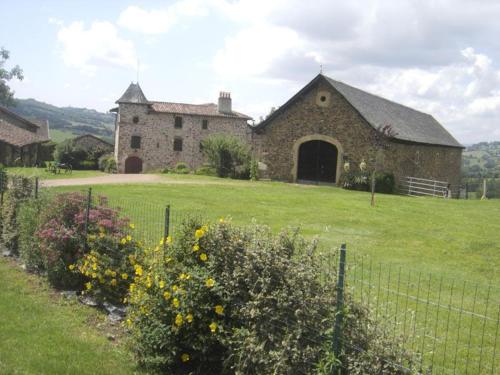 un gran edificio de piedra con una cerca en un campo en Le gîte de caractère, en Flagnac