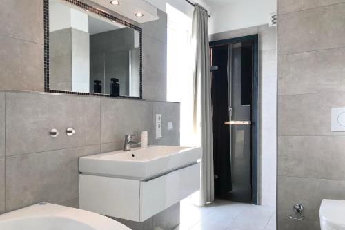 ein Badezimmer mit einem weißen Waschbecken und einem Spiegel in der Unterkunft NordseeResort Friesland NordseeResort Friesland 1 in Schillig