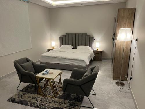 a bedroom with a bed and two chairs and a table at تلال الفخامة in Hail