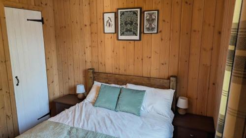 a bedroom with a bed with two pillows and pictures on the wall at Bracken Lodge in Dalavich