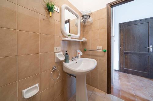 La salle de bains est pourvue d'un lavabo, d'un miroir et d'une porte. dans l'établissement Vista Pista da Sci - Aprica Centro - 2min da Skilift, Wifi, à Aprica