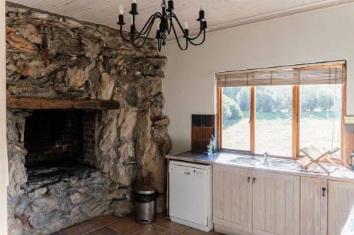 a kitchen with a stone fireplace and a sink at Barton Luxury Villas in Botrivier
