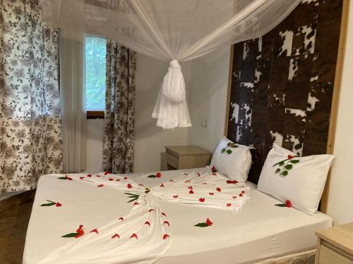 a bedroom with a white bed with red roses on it at pasha nungwi zanzibar in Nungwi
