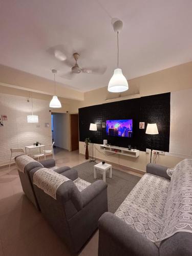 a living room with couches and a flat screen tv at Electrifying 2BHK Gateways in Bengaluru