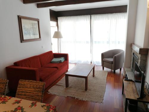 a living room with a red couch and a chair at Esterri Confort in Esterri d'Àneu