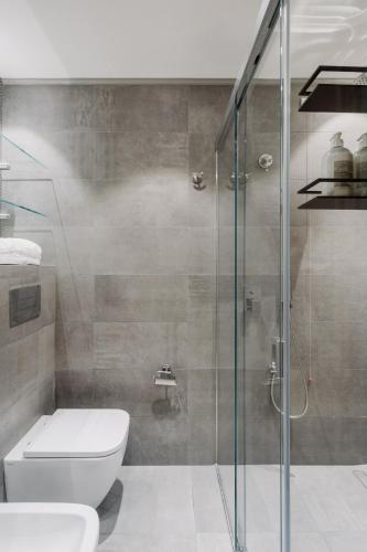 a bathroom with a toilet and a glass shower at Hotel Aquadulci in Chia