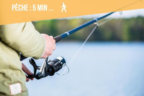 a man holding a fishing rod with a camera at La Chaumière des 2 Cygnes-SPA- WIFI-Parking-Calme in Abbeville