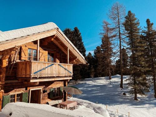a log cabin in the snow with an umbrella at Turracher Hütte in Turracher Hohe