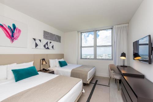 een hotelkamer met 2 bedden, een bureau en een raam bij Amazing Apartments At H Beach House in Hollywood