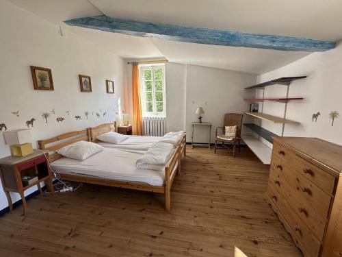 Un dormitorio con una cama y un escritorio y una ventana. en La masqueria, en Montgaillard