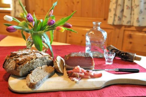 a cutting board with bread and a vase with flowers at Hoamatlhütte in Schladming