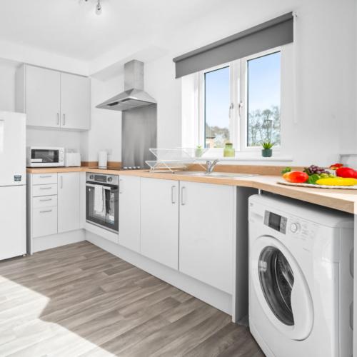 a kitchen with white cabinets and a washer and dryer at Modern Two Bedrooms Apartment - Parking - Netflix 51C in Netherton