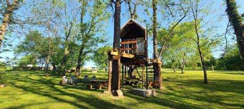 a tree house in the middle of a field at Tree House Glamping Destination near the Ozarks, with River Access for Swimming and Fishing in West Liberty