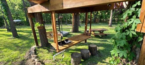a tree house with a swing in a park at Tree House Glamping Destination near the Ozarks, with River Access for Swimming and Fishing in West Liberty