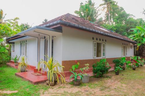 una pequeña casa blanca con plantas delante en VN45 Villa in Ahangama, en Ahangama