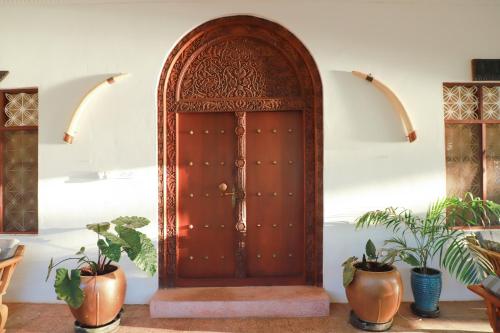 a wooden door in a room with potted plants at Emerald Sunset Villa in Zanzibar City