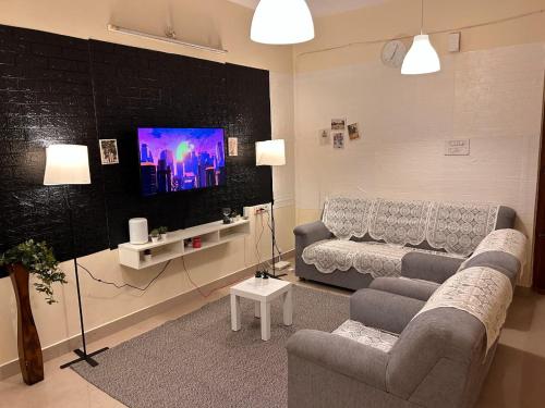 a living room with a couch and a flat screen tv at Electrifying 2BHK Gateways in Bengaluru